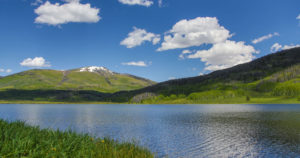 Rolling green hills, lake and blue sky with clouds in Steamboat Springs, CO